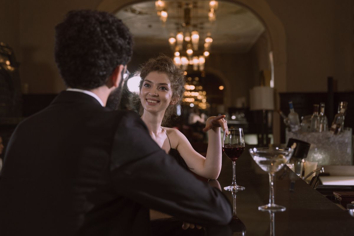 A couple sharing wine and cocktails while talking on a date at a cozy bar