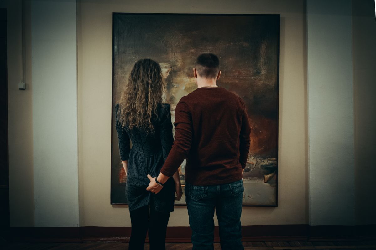 A couple admiring a painting together during a relaxed art gallery date