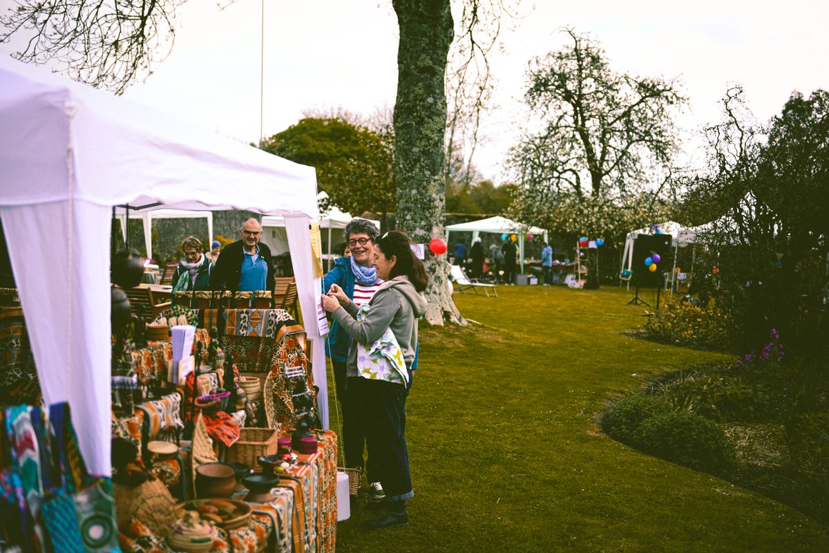People browsing stalls and tents at an open-air art and craft market in a park