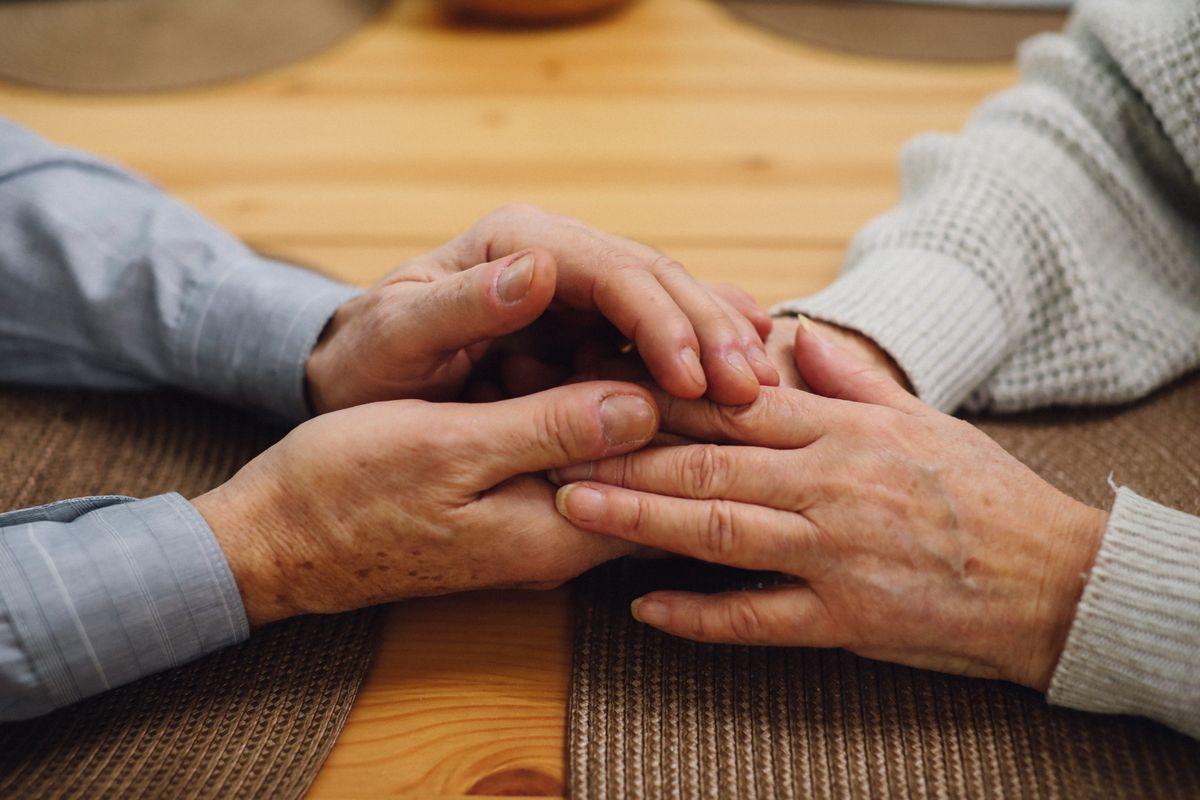 Close-up of an older couple's hands resting together, a sign of quiet companionship