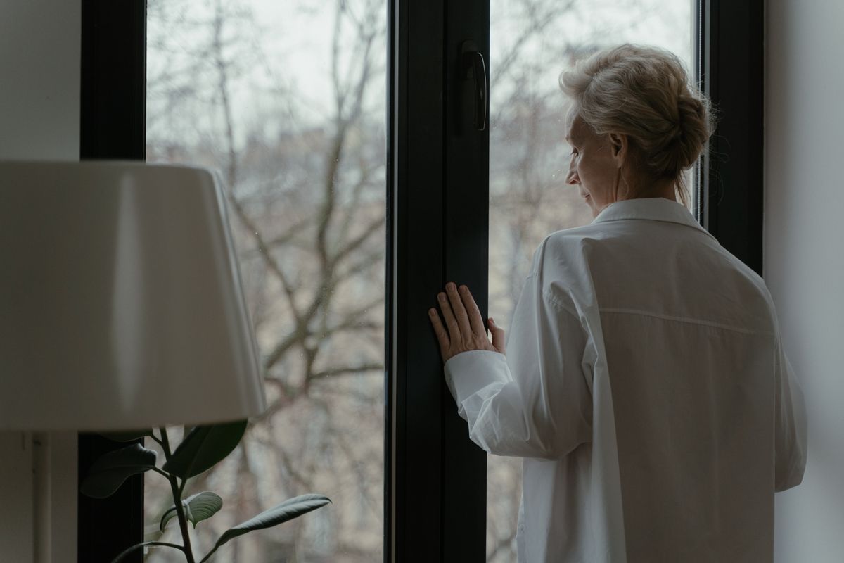 An elderly woman gazing peacefully through a window, alone with her thoughts