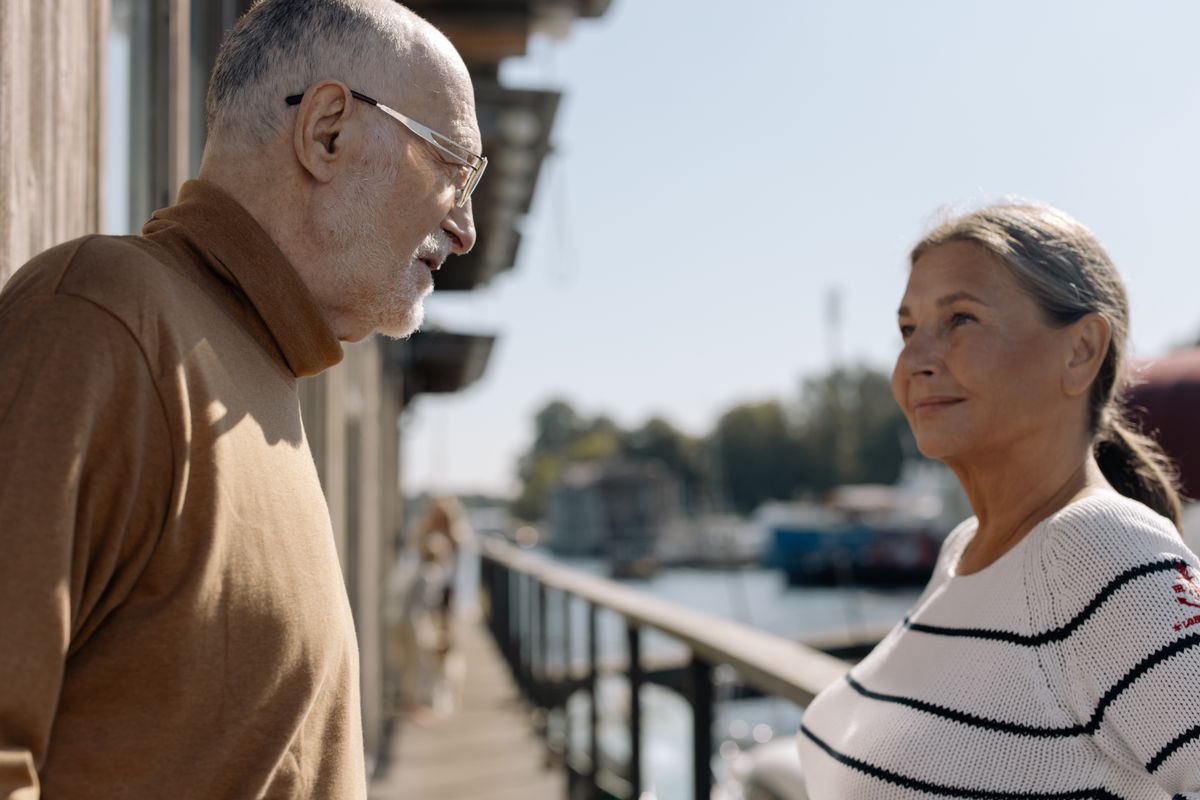 A relaxed senior couple smiling together by the water on a sunny day