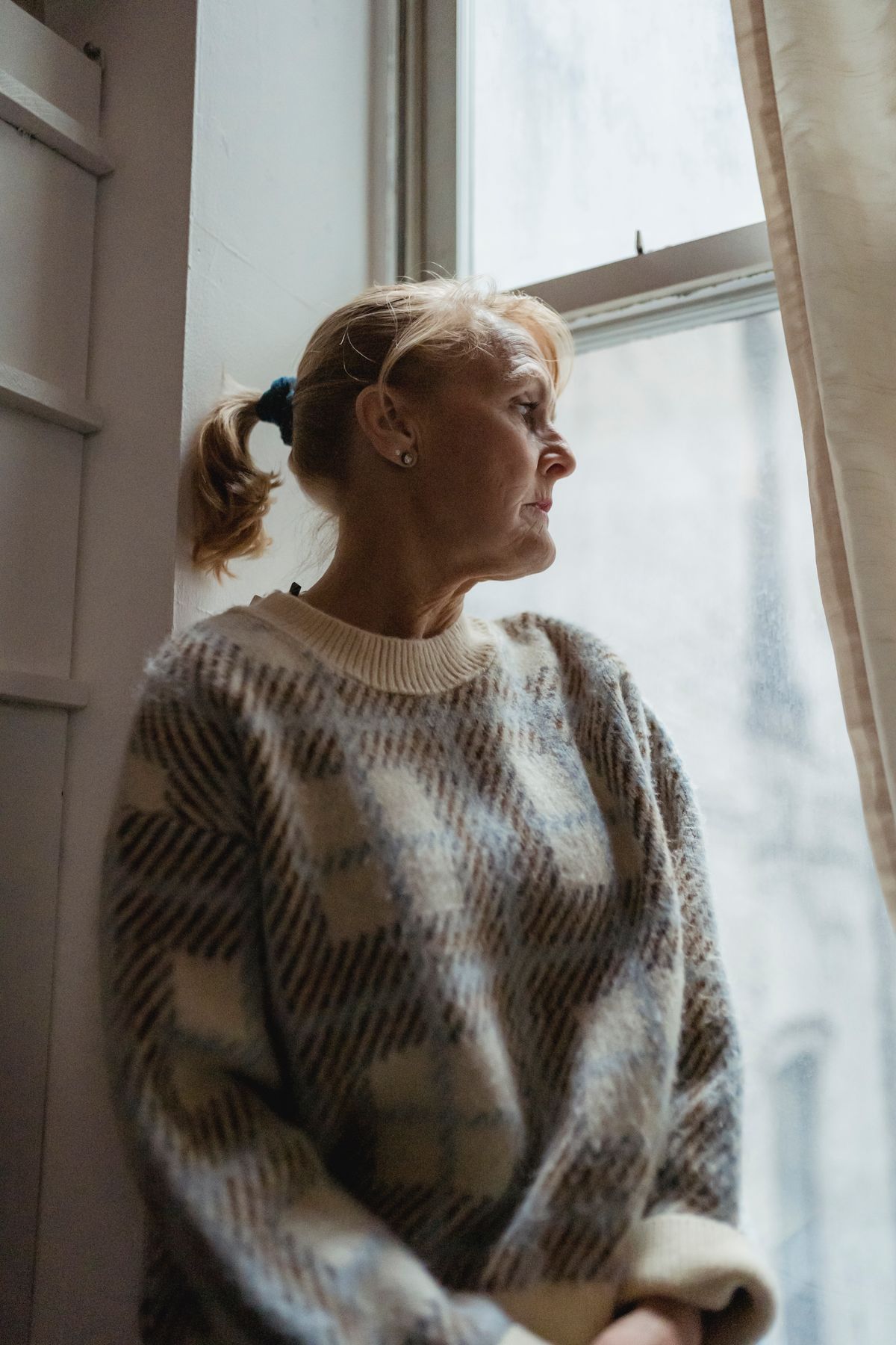 A thoughtful mature woman gazing out a window, reflecting on what she truly wants in a partner