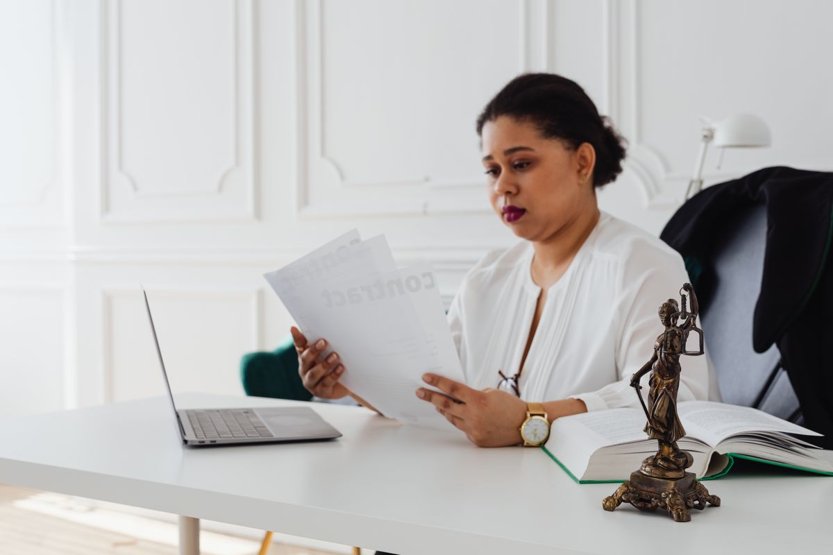 A professional woman carefully reviewing documents at her desk during a background-screening process
