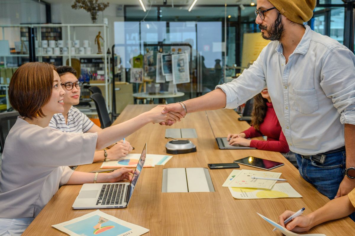 Two professionals shaking hands across a conference table, signaling a vetted and trusted introduction