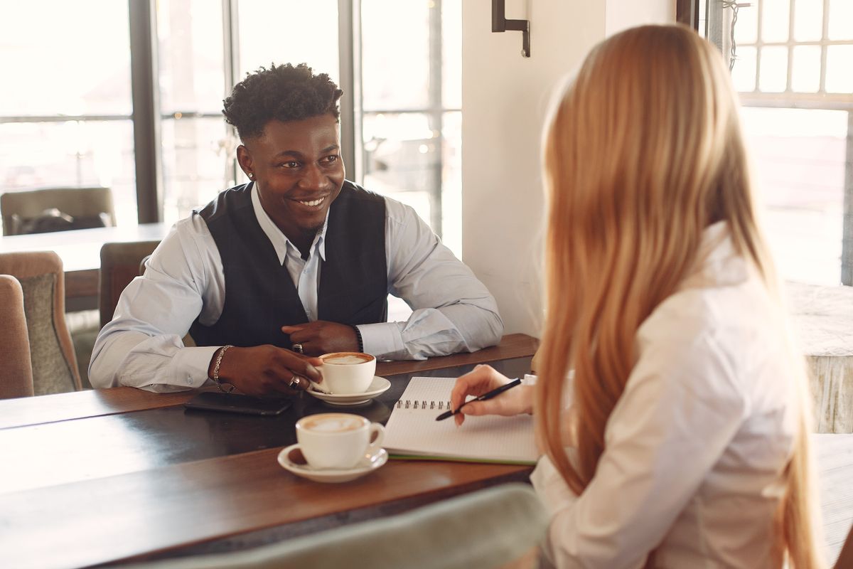 Two people in a warm one-on-one conversation over coffee, like a personal matchmaker consultation