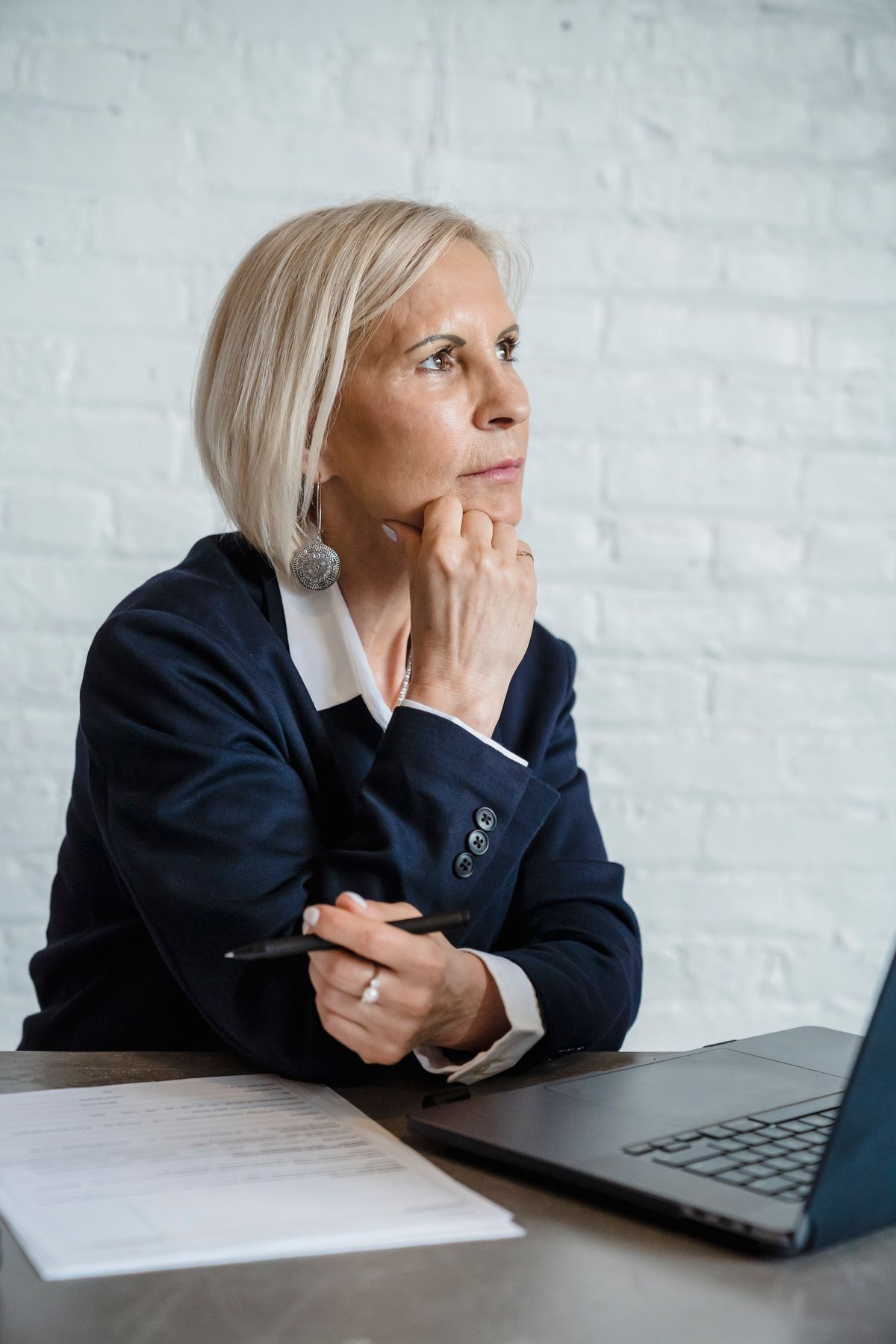 A woman weighing her matchmaking options thoughtfully at a laptop with notes