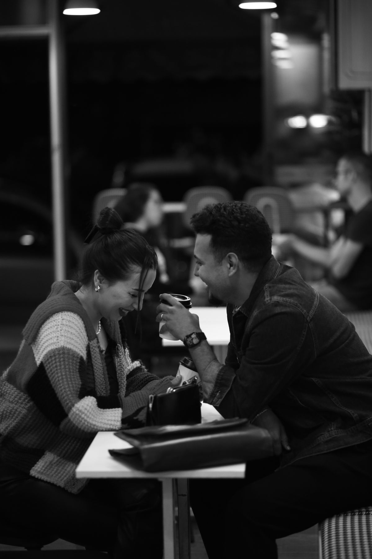 A young couple laughing together at a street cafe table