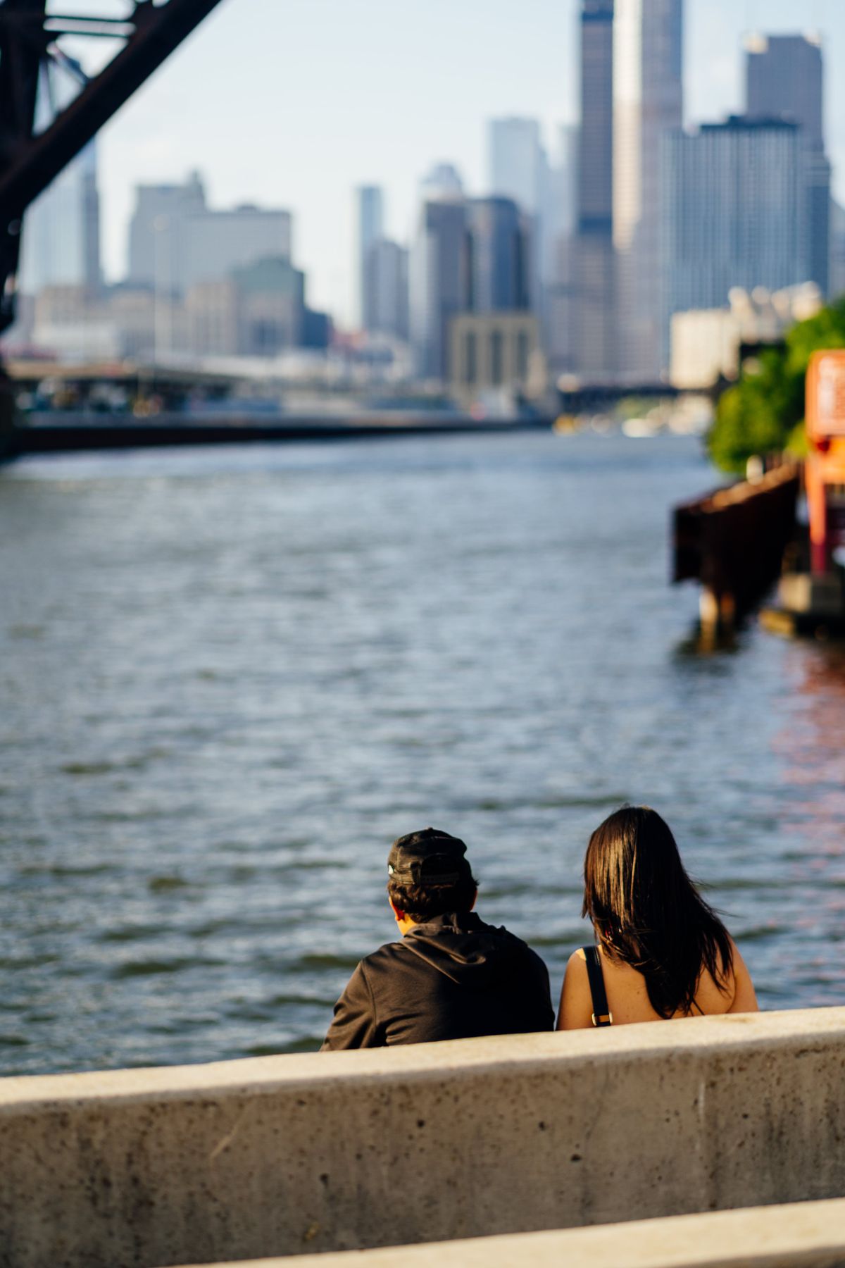 A couple sitting on a bench facing the Chicago River and downtown skyline