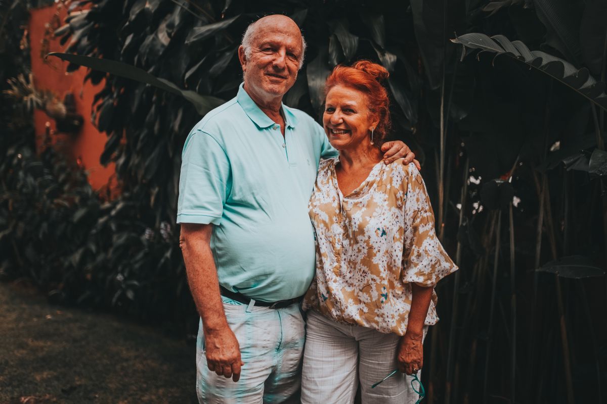 A happy mature couple smiling together outdoors surrounded by greenery